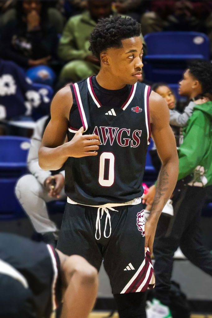 A basketball player in a black Dawgs uniform with the number 0 stands courtside