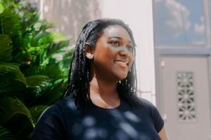 Teenage girl smiling in black shirt posed outside in front of some greenery