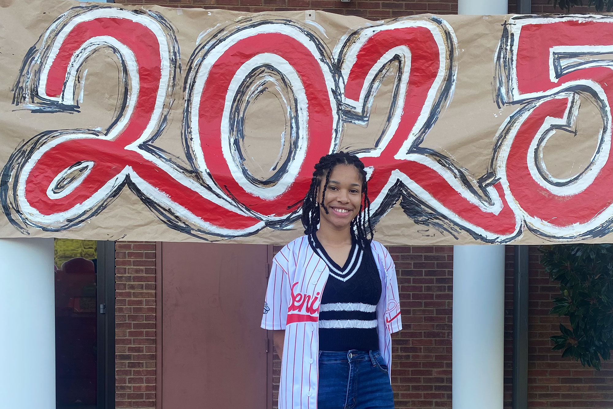 A young lady standing in front of sign that reads 2025
