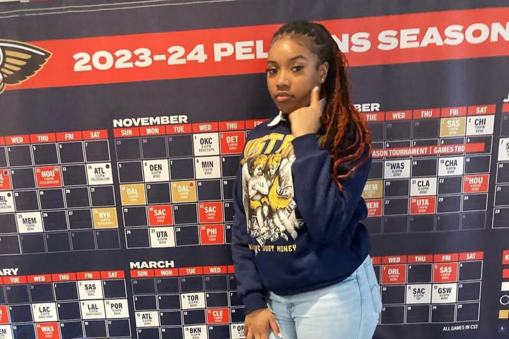 A teen stands in front of a sport team calendar of games