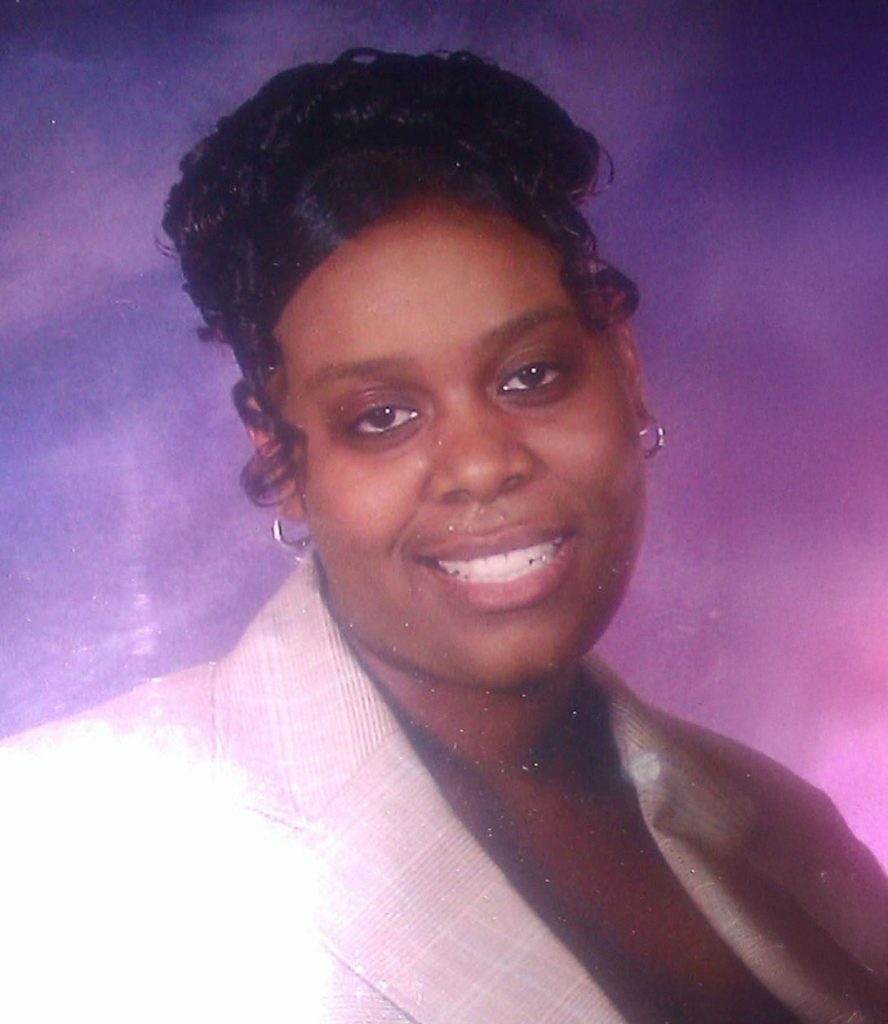 A woman in a portrait wearing a white top, posed against a purple background