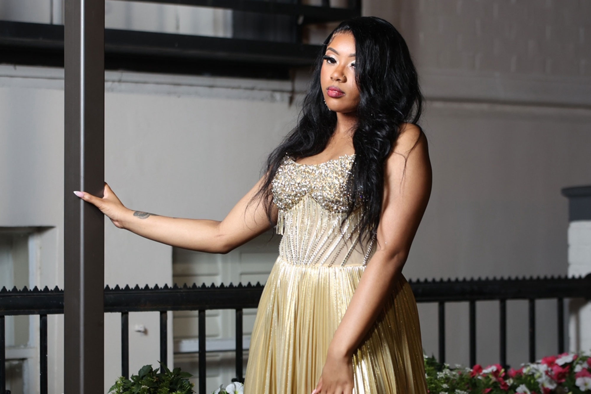 Madison Ford posing and leaning on a pole in a gold prom dress