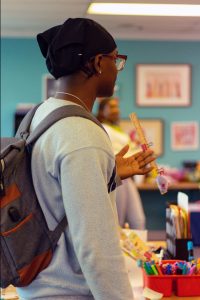 Young man in an office with a gray sweatshirt and a backpack