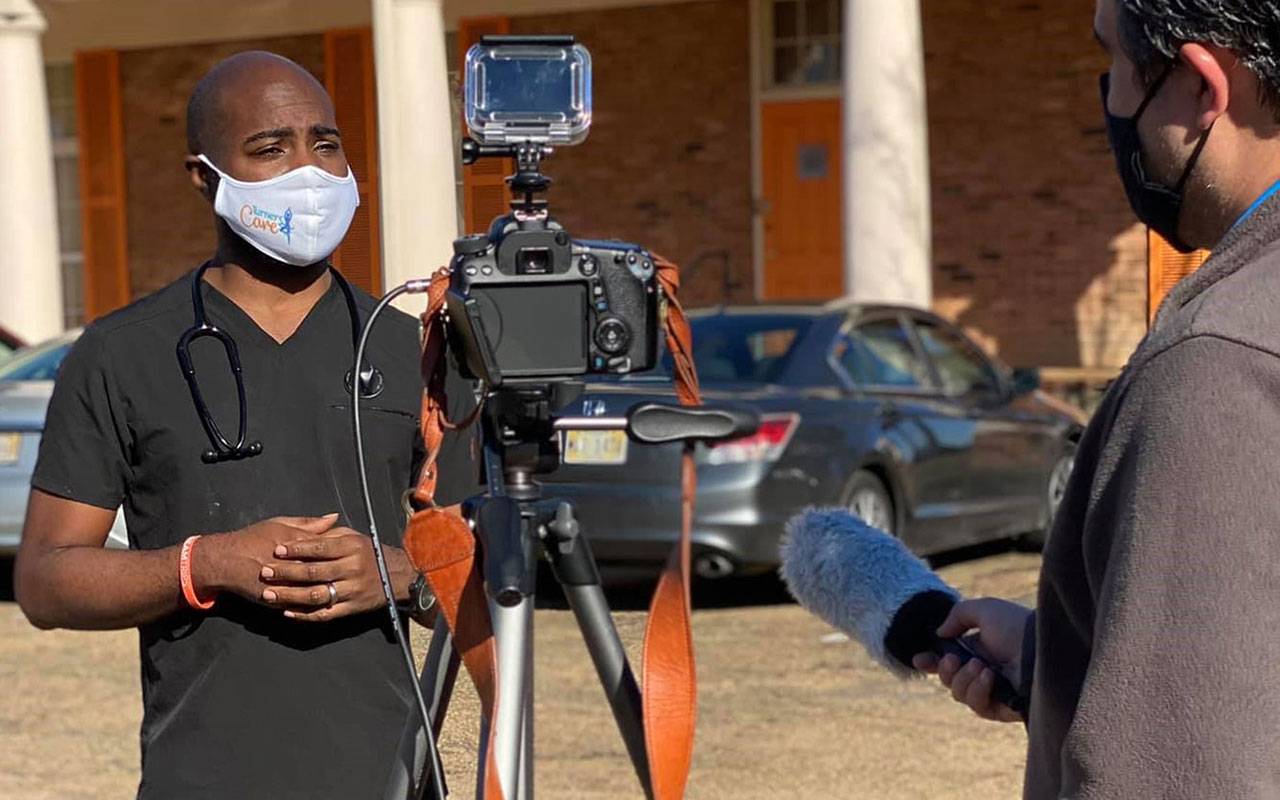 Dr. Justin Turner stands in front of a camera for a news interview