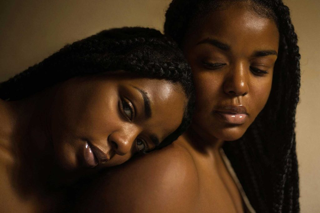Two black women lean against each other